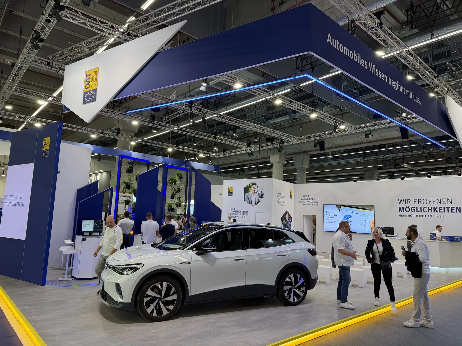 DAT-Stand auf der Automechanika Frankfurt 2026 mit einem weißen Auto und Besuchern - ein Anbieter von Fahrzeugdaten und -bewertungen aus unserem Integrationsregister