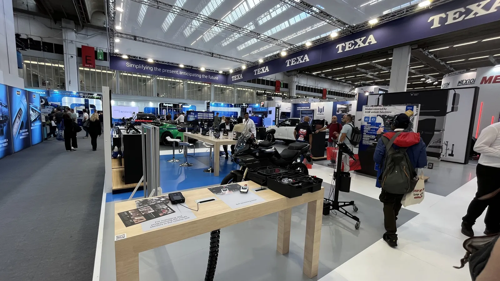 Stoisko TEXA na Automechanika Frankfurt 2026 - stół z urządzeniami diagnostycznymi i motocykl w hali targowej